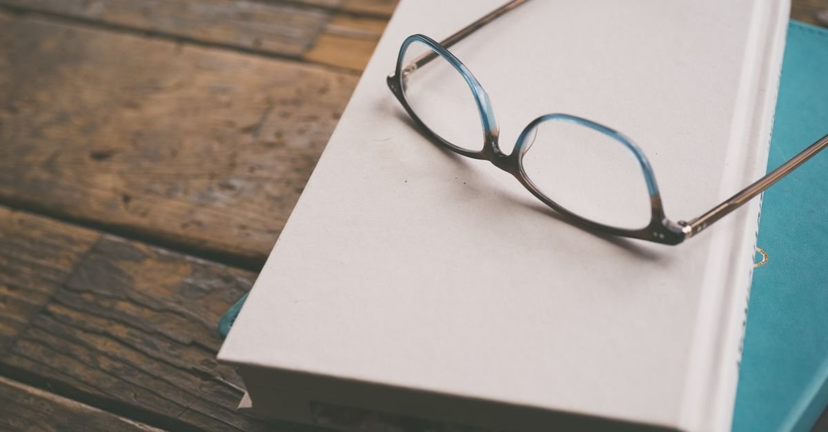 Reading glasses resting on a closed plain book, standing in for manuals that never mention adhd brain fog.