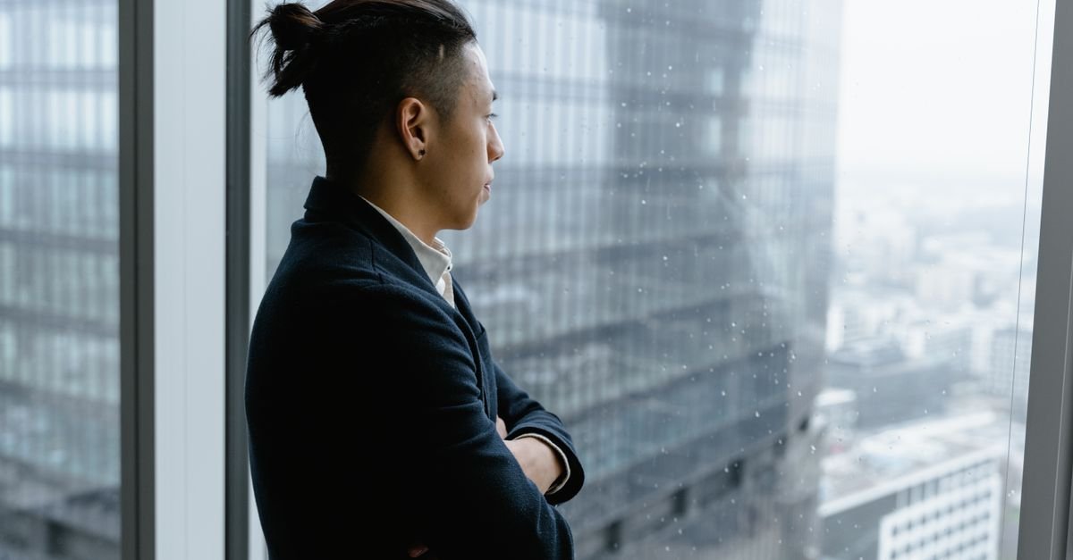 A man looking out of an office window on a rainy day