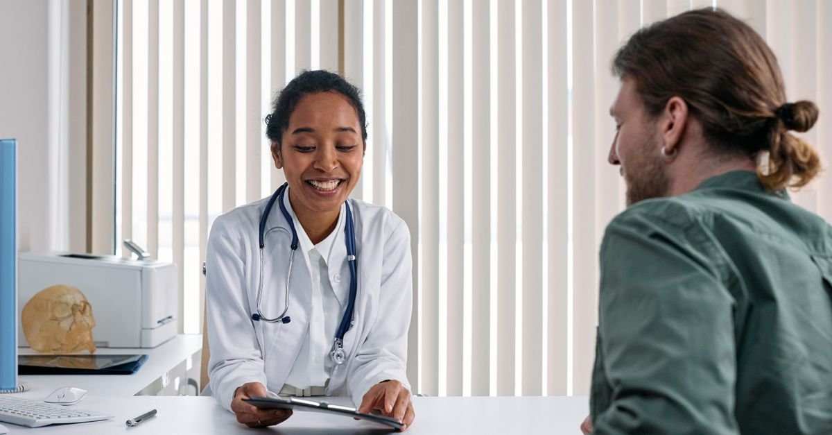 Doctor at a desk listening to a patient in a bright consulting room, describing brain fog to a doctor