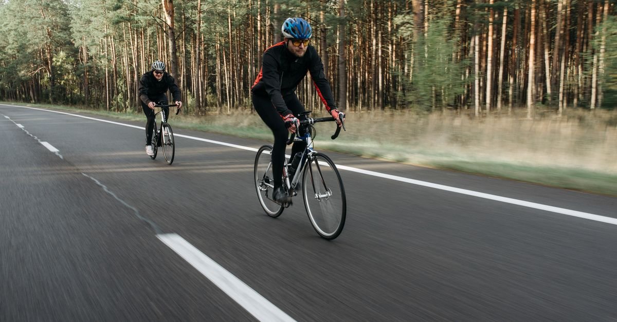 Cyclist riding alone on an open road, illustrating mental tiredness shortening endurance